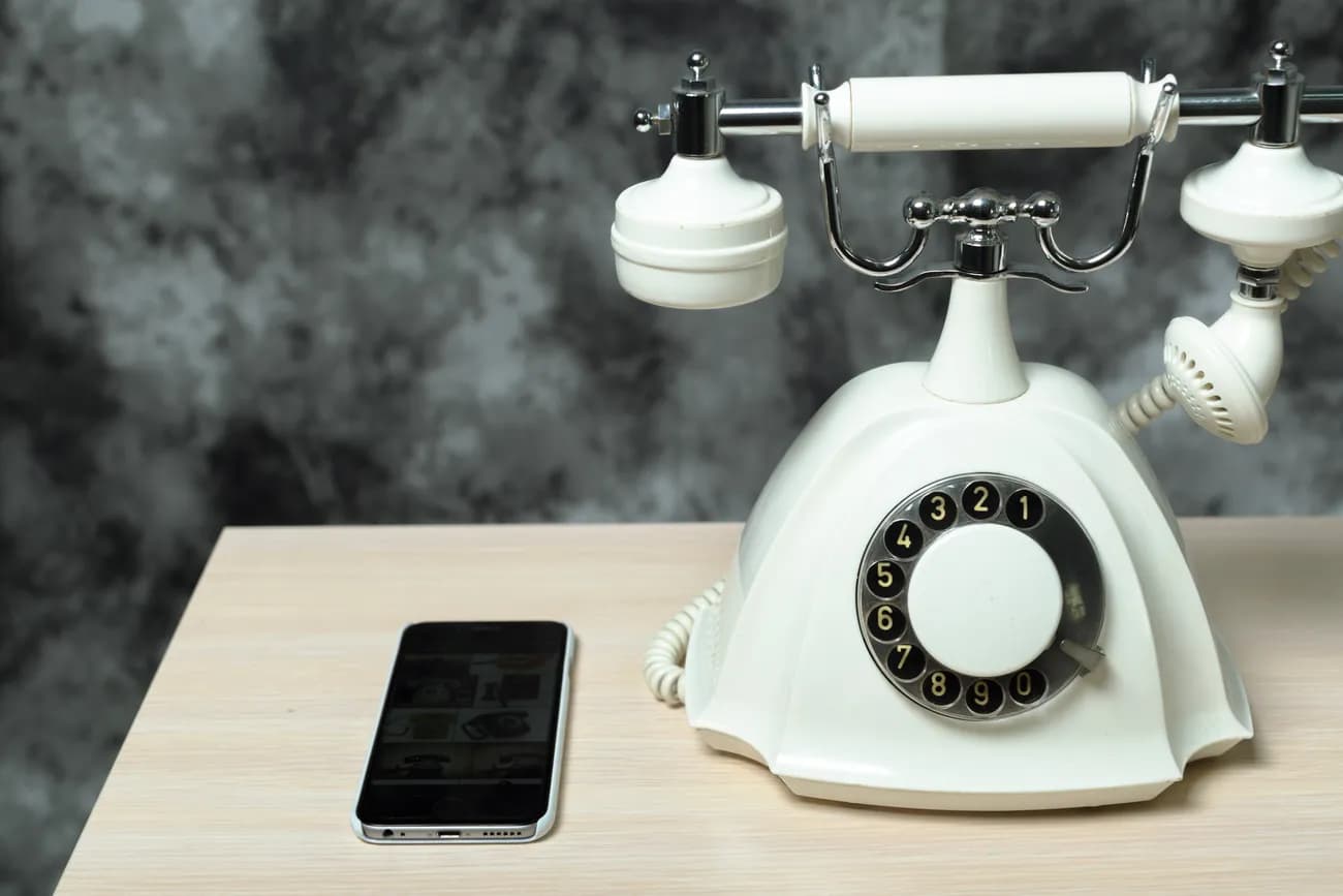 Vintage rotary phone beside modern smartphone illustrates traditional vs AI answering services for businesses.