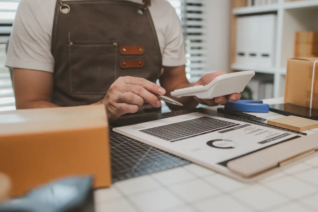 Small business owner calculates pricing for a phone answering service using a calculator.